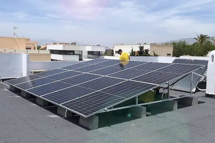 Imagen de placas solares instaladas por Imelect en el terrado de una vivienda junto a un operario de la empresa